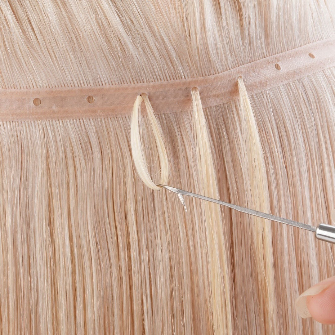Stylist threading natural hair through a DULGE Butterfly Weft bead hole with a loop tool